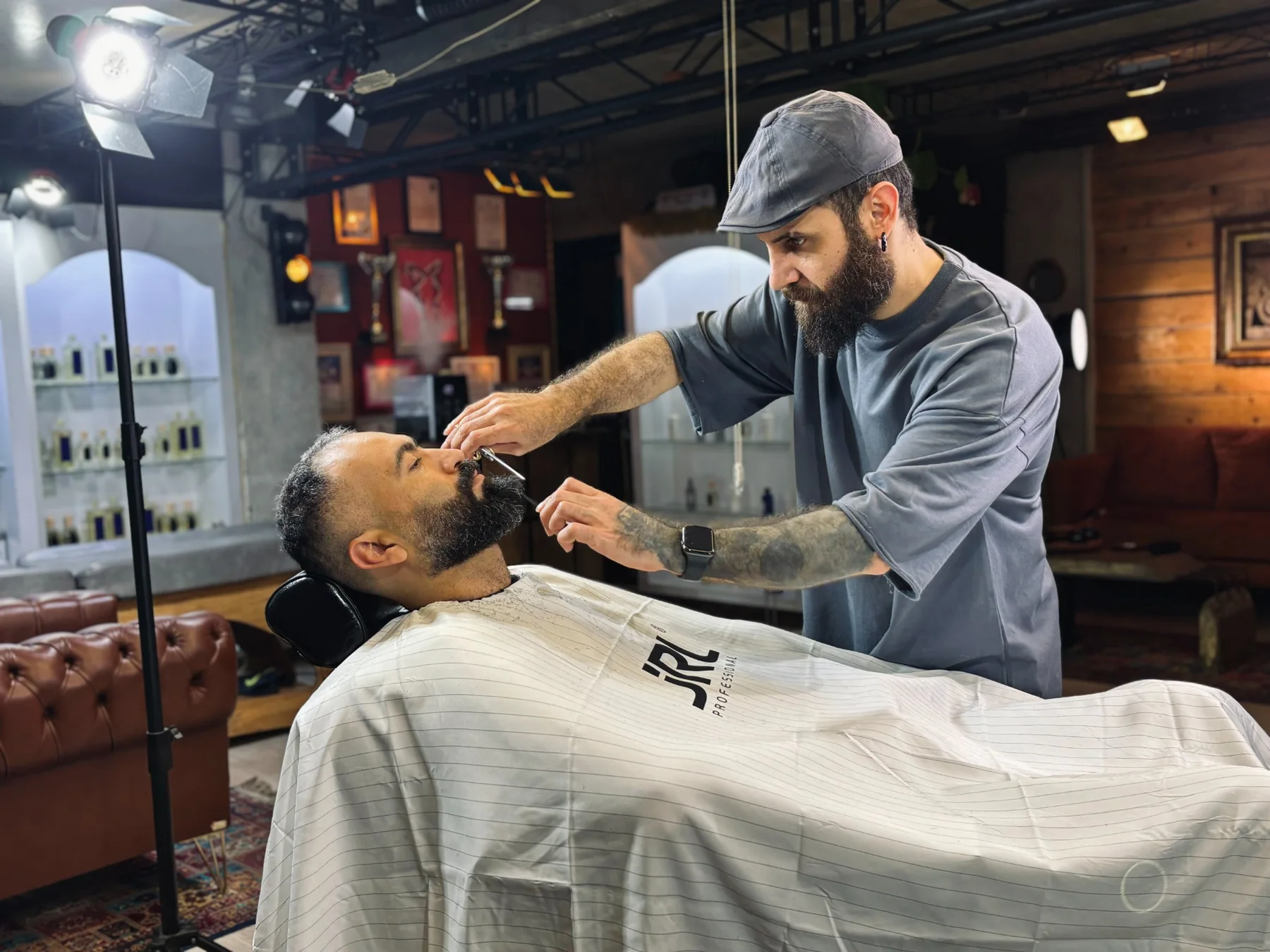 Barber working on a client's beard with a straight razor, full concentration