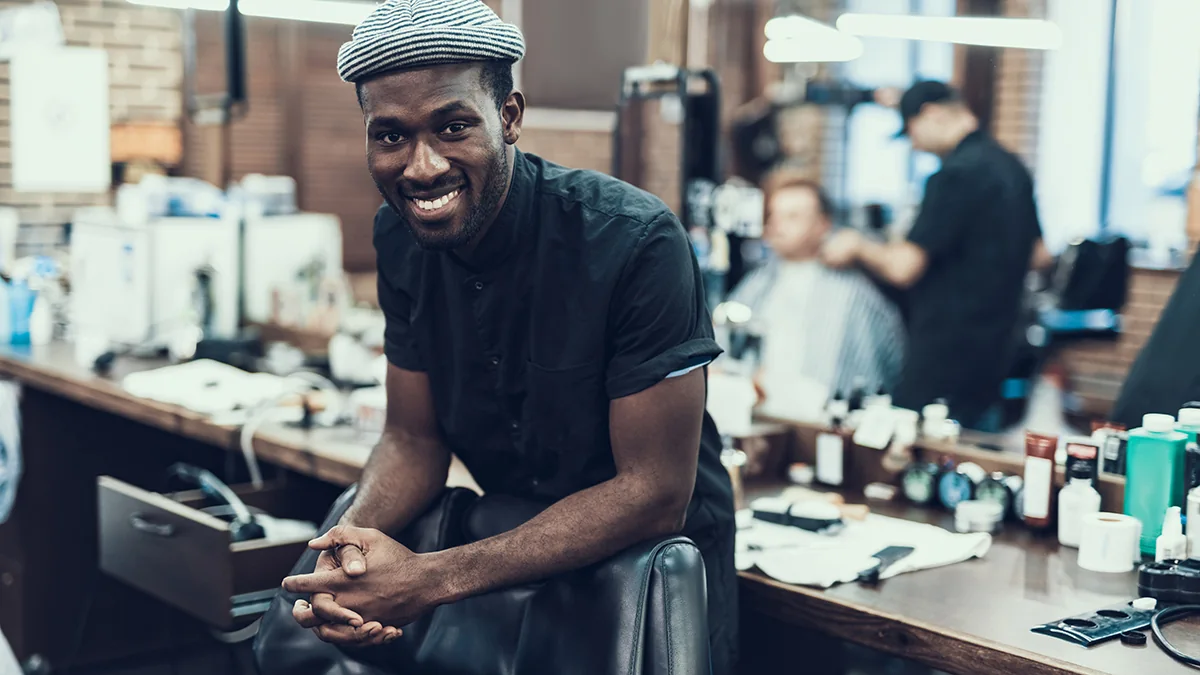 Barber relaxed at his station with grooming products on the counter