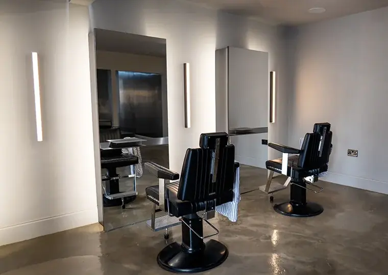 Marbello's barbershop — clean black leather chairs, warm wall lighting
