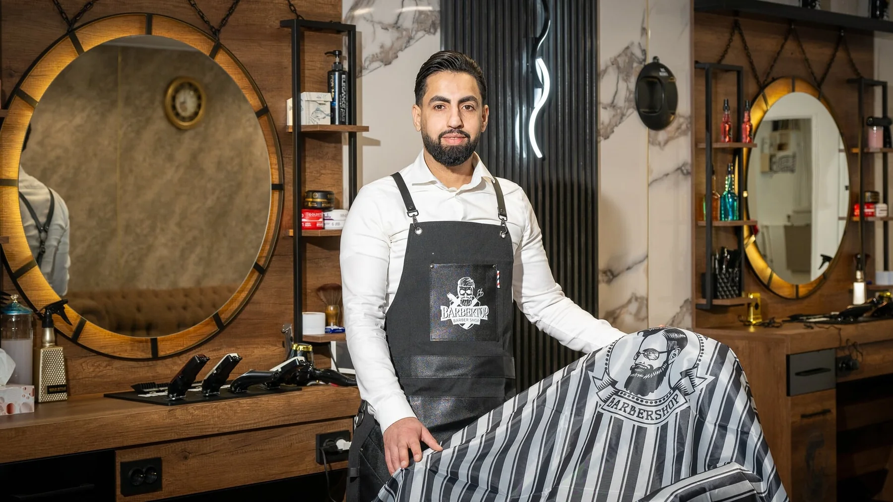 Mateo — founder, standing in the shop holding a barber cape